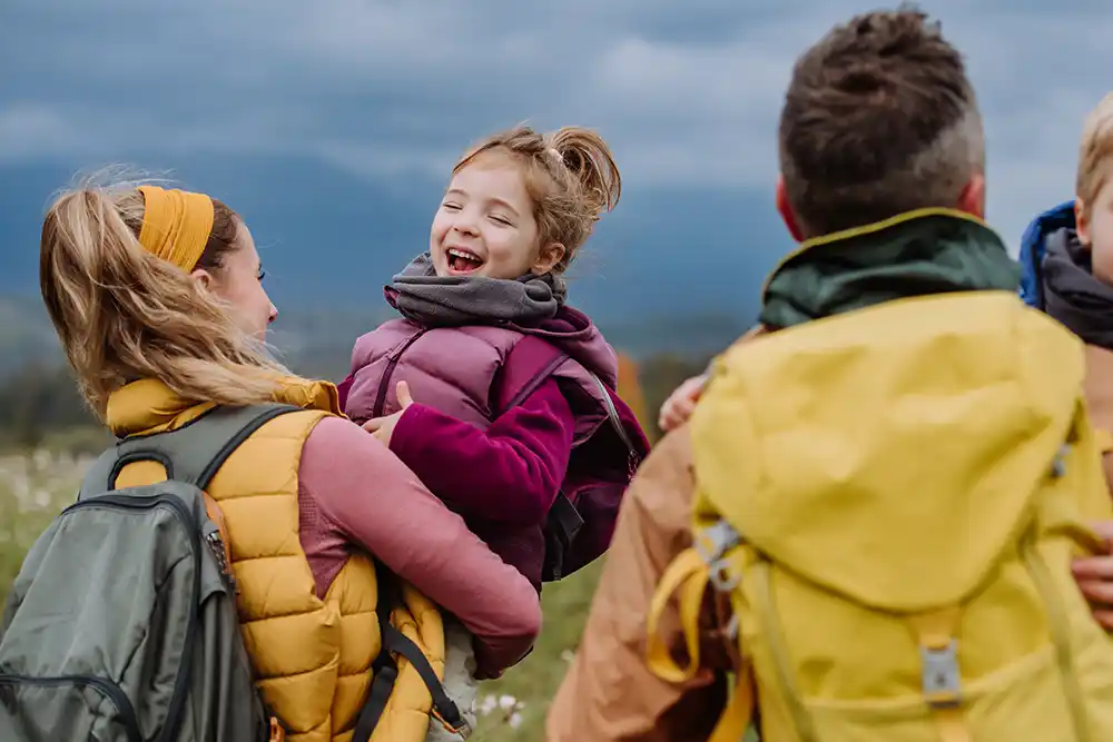 A child smiles as she's held by her mother and her father next to them